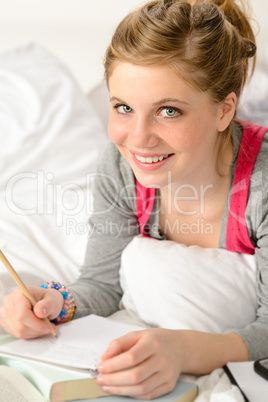 Smiling girl preparing for exams in bed