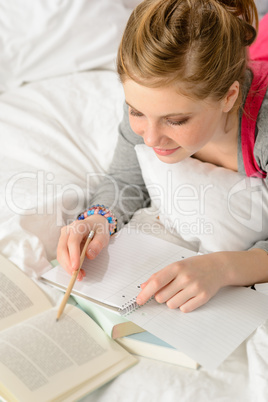 Teenage girl concentrating on studying in bed