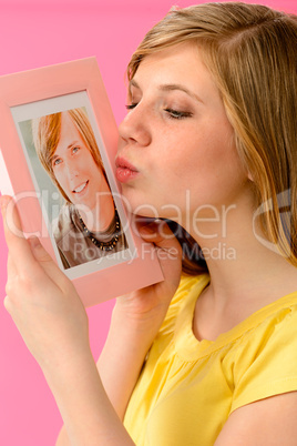 Young girl holding and kissing boyfriend's picture