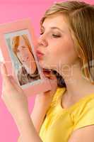 Young girl holding and kissing boyfriend's picture