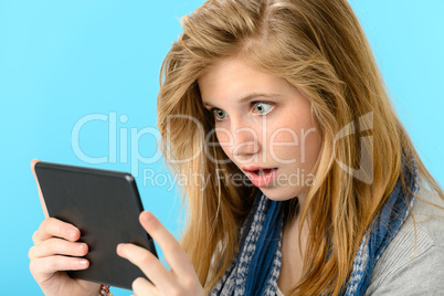 Surprised young girl holding digital tablet