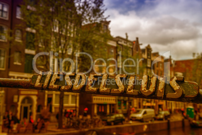 Amsterdam. Bridge sign over city canals and buildings in spring