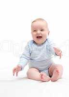 beautiful laughing happy baby boy sitting on white bed