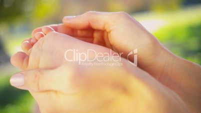 Gentle Hands Cradling Baby Foot in Close up