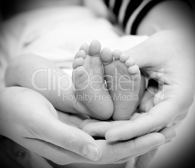 Small feet baby holds his mother in her hands