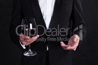 Fragment of stylish man in elegant black tuxedo with glass red w