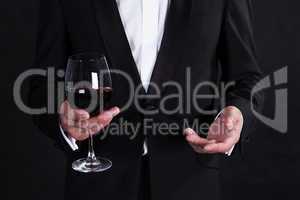 Fragment of stylish man in elegant black tuxedo with glass red w