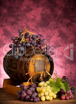 White and red grapes with wine barrel