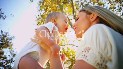 Young Mom Kissing Baby Son Outdoors