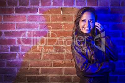 Mixed Race Woman Using Her Cell Phone Against Brick Wall