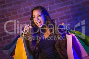 Mixed Race Young Woman Holding Shopping Bags Against Brick Wall
