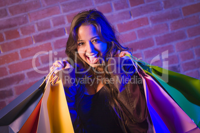 Mixed Race Young Woman Holding Shopping Bags Against Brick Wall