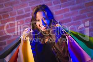 Mixed Race Young Woman Holding Shopping Bags Against Brick Wall