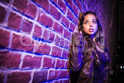 Frightened Pretty Young Woman Against Brick Wall at Night