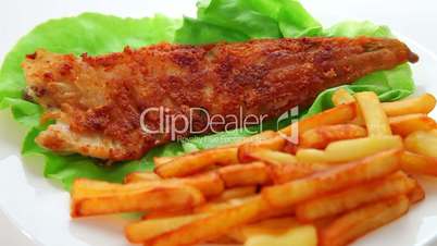 Fried fish dish - fish fillet on green salad with chips dolly shot