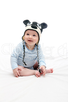 beautiful laughing happy baby boy sitting on white bed in knitte