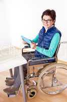 Woman with Tablet PC's in a wheelchair at the table