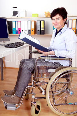 Disabled woman in wheelchair at desk