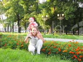 Happy mum and the daughter in park with flowers