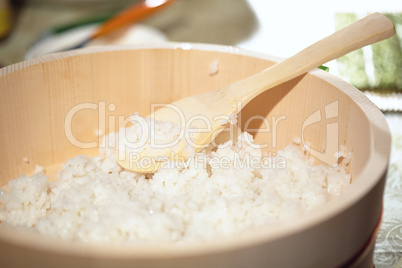 Cooking sushi. Mixing rice in a wooden plate.