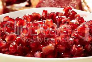 Pomegranate seeds in a white bowl.
