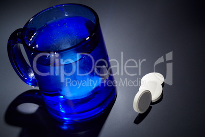 Tablet dissolving in a blue glass of water.