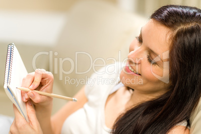 Happy woman taking notes into notepad