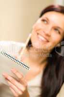Smiling thinking woman holding notepad
