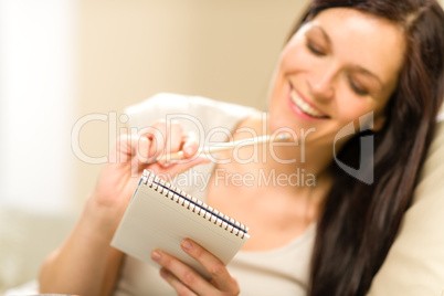 Pensive brunette woman writing to notebook