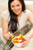 Joyful woman eating bowl of fresh vegetables