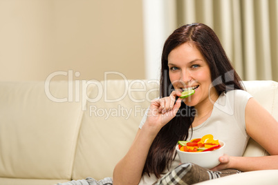 Woman sitting on sofa eating mixed salad