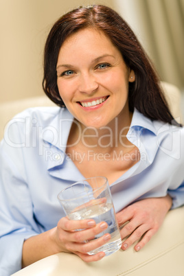 Joyful young woman holding glass of water