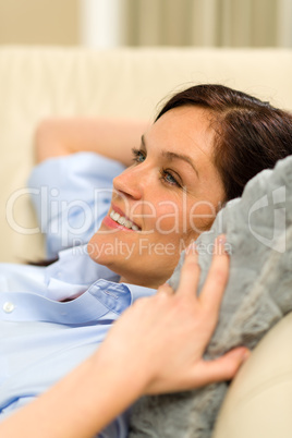 Smiling young woman lying on sofa