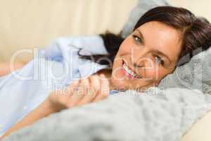 Smiling brunette woman lying in bed
