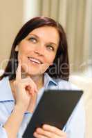 Pensive cheerful woman holding digital tablet