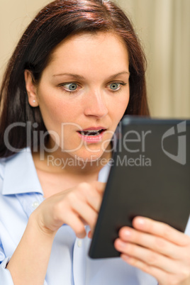 Astonished woman reading on digital tablet