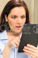 Astonished woman reading on digital tablet