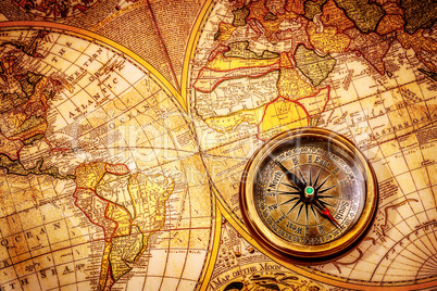 Vintage compass lies on an ancient world map.