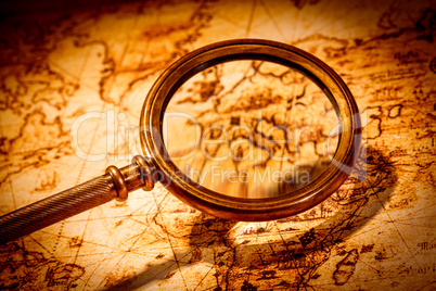 Vintage magnifying glass lies on an ancient world map