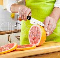 Woman's hands cutting grapefruit