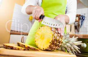 Woman's hands cutting pineapple