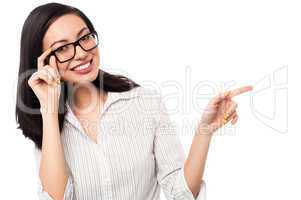 Woman adjusting her spectacles and pointing away