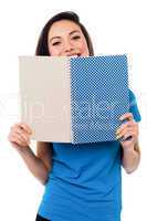 Young girl hiding her face with notebook
