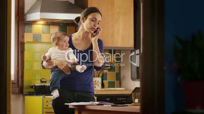 Multitasking mother working with computer, holding little girl at home