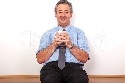 Man with cup sitting on the floor