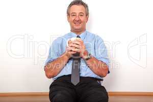 Man with cup sitting on the floor