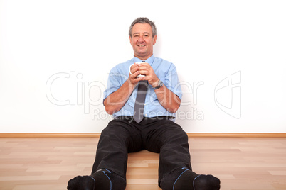 Man with cup sitting on the floor