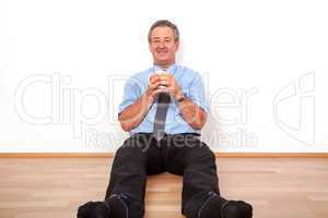 Man with cup sitting on the floor