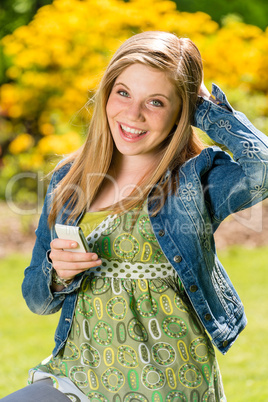 Perky female teenager texting in the park