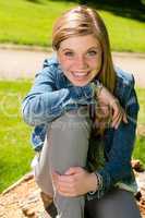Cheerful teenage girl sitting in the park